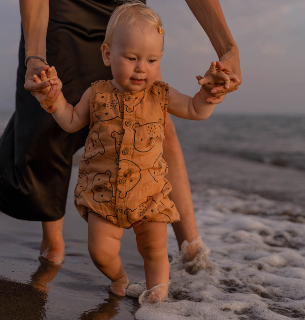 Mother supporting baby walking